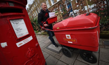 A Royal Mail delivery worker pushes a red mail cart down a street of Victorian houses in London, past a red postbox