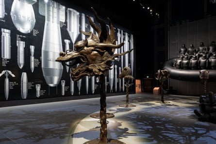 traditional bronze sculptures at the exhibition mounted on short poles. in the foreground a chinese dragon’s head