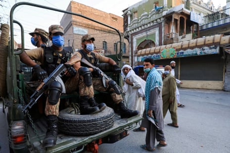 People walk past an army vehicle, patrolling on the street to enforce coronavirus safety protocols, as the spread of Covid-19 continues in Peshawar, Pakistan on 25 April, 2021.