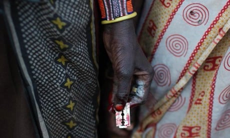 A black woman's hand holding a razor blade against printed fabric