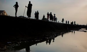 Refugees from Leer walk along the edge of a drainage chanel in in the in Protection of Civilian (POC) camp in the evening light in Bentiu, South Sudan