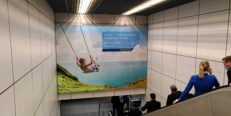 Billboard ad featuring image of a child on a swing and blue ocean and sky, and bearing slogan 'join us in creating a more sustainable future'