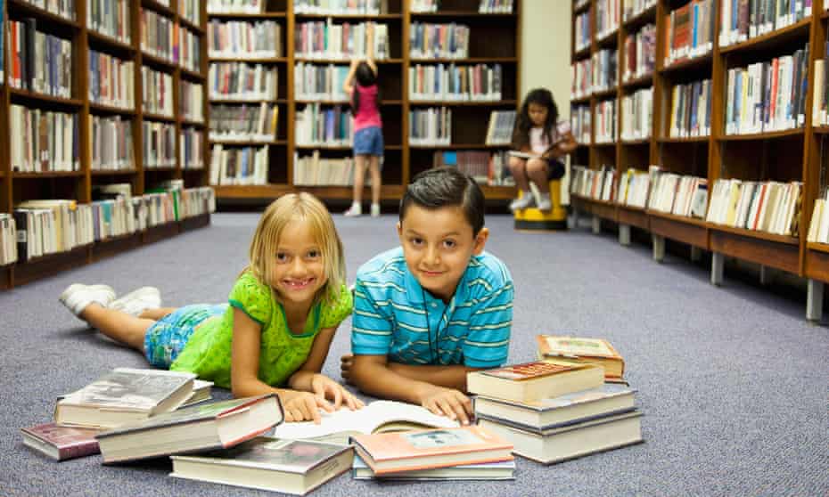 Children reading books on a library floor.