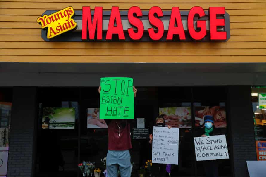 People hold signs outside Young’s Asian Spa following the deadly shooting.