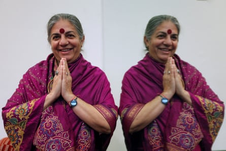 A mirror image of a woman in a purple sari holding her hands in the namaste gesture
