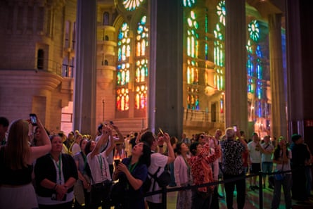 Tourists taking photos inside, lit by stained-glass windows