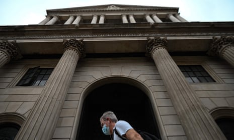 A man wearing a face mask walks past the Bank of England