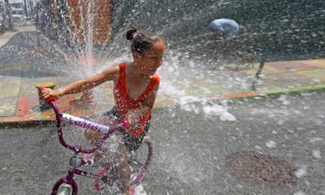 A person cools off in spraying water from a fire hydrant in the Kensington neighborhood of Philadelphia