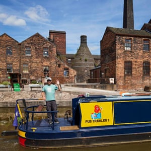 A bottle oven is seen in the background at Middleport Pottery, Burslem. A man waves from a canal boat in the foreground