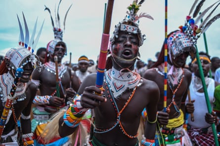 Maasai men dressed in ceremonial beads and headdresses, carrying spears.