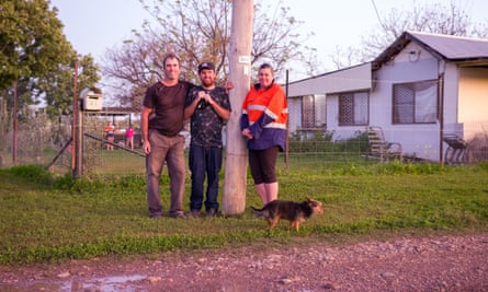 Michael, Brandon and Erin Edmunds stand next to the November 2021 high-water mark on a power pole in front of their house