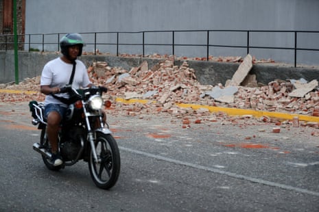 A motorcyclist rides past debris