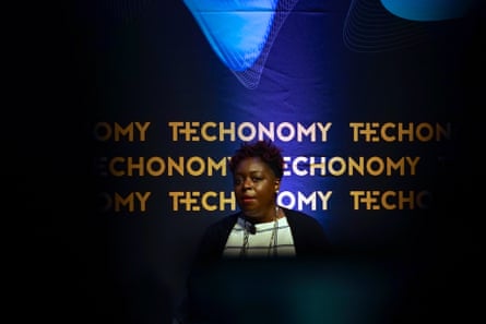 Woman speaking at a lectern with Technomy written on a blue backdrop behind her.