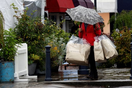 Shopper shelters under an umbrella while carrying bags at Bicester Village