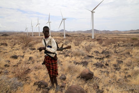 A Turkana herd boy carries his gun as he follows his goats near wind turbines at the Lake Turkana Wind Power project in Marsabit County, northern Kenya