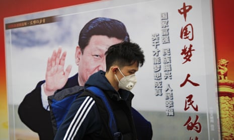 A man wearing a mask for protection against pollution walks by a poster featuring Chinese President Xi Jinping and the words, in red, “China Dream, People Dream”, along a street in Beijing 