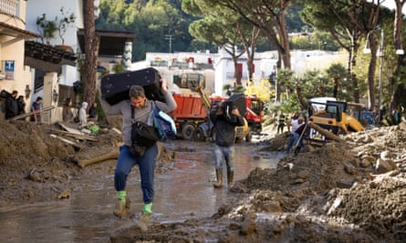Men carry possessions through a street covered in mud after landslides on Ischia.