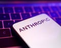 The Anthropic logo seen on a smartphone next to a keyboard lit in neon purple