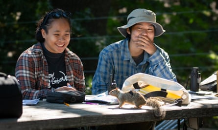 Tia Ravara (UW-EauClaire) and Ryann Su (UC Davis) watch as a squirrel hops on to a table in front of them