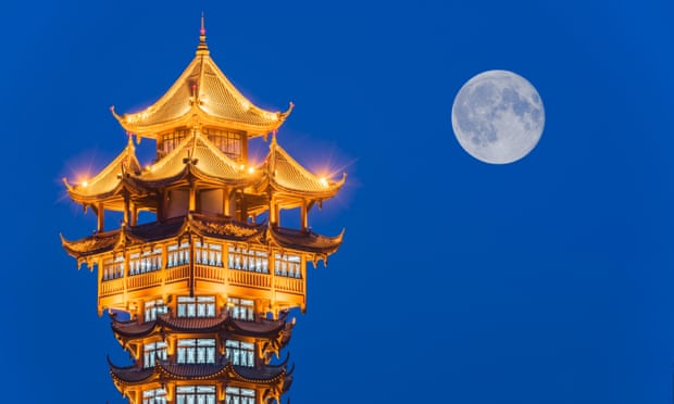 Jiutian Tower illuminated at night with full moon in the background, Chengdu, China.