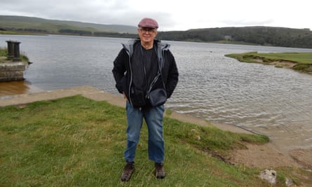 Man in his 60s standing in front of a lake