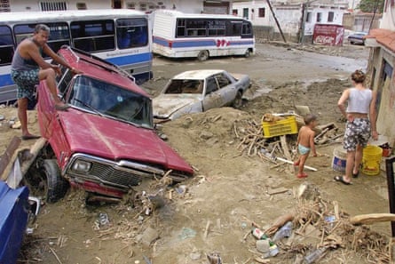 A man looks at the damage to a mud filled street after heavy rains spawned mudslides and floods