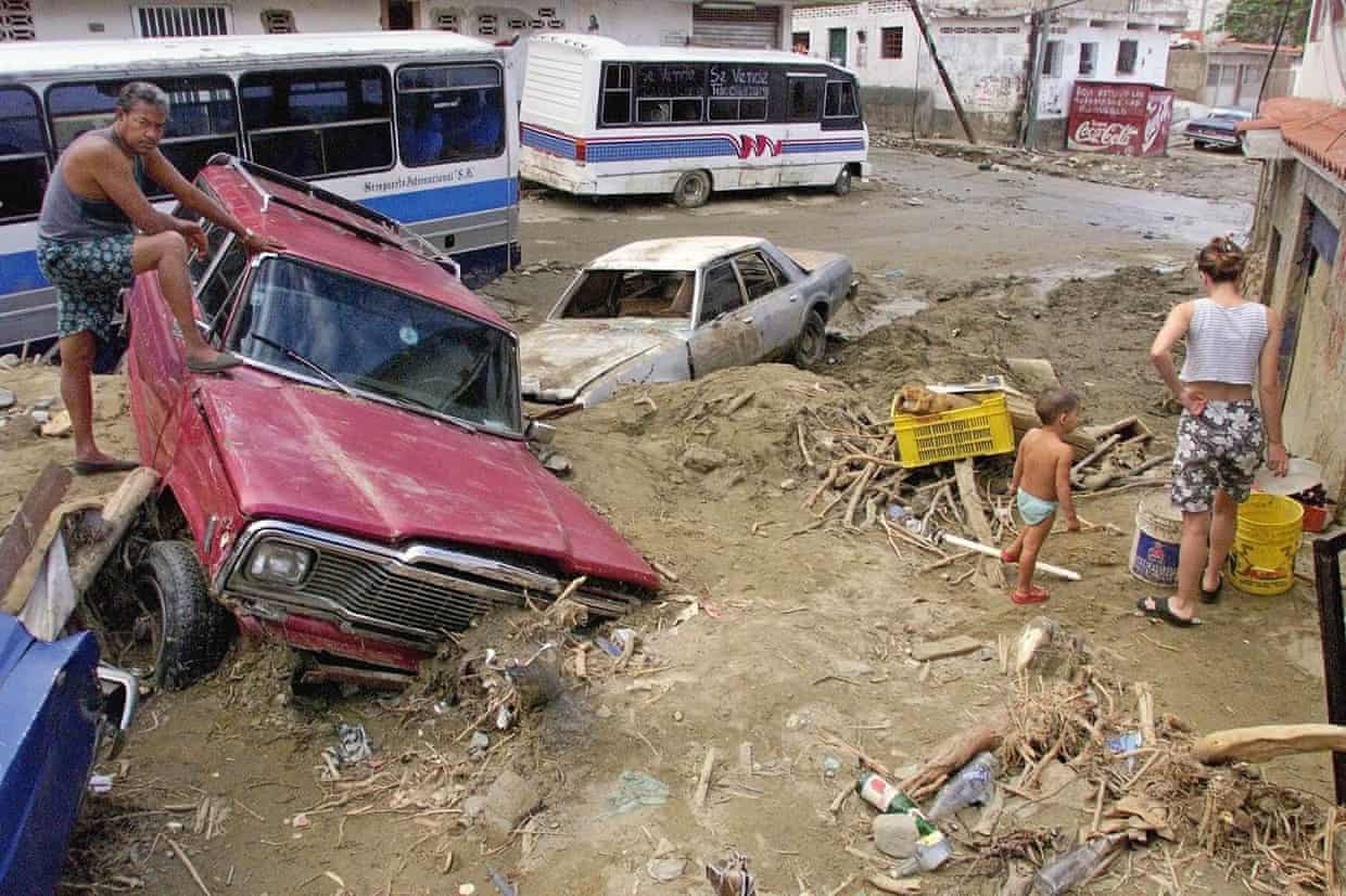A man looks at the damage to a mud filled street after heavy rains spawned mudslides and floods