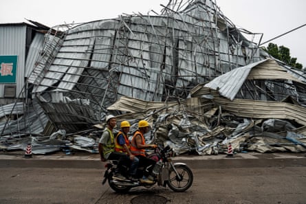 People drive past a crumpled building after a tornado hit Guangzhou