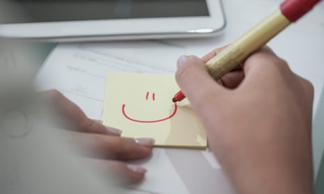 Close-up of woman at desk drawing a smiley face