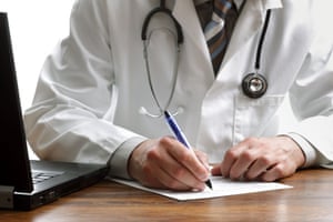 a close up of a male doctors hand writing a prescription