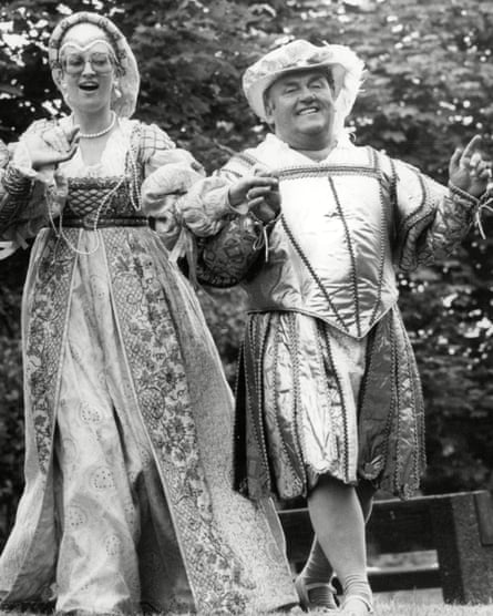 A black and white shot of a man and woman holding hands dressed in tudor clothes.