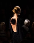 Model wears open back black dress.