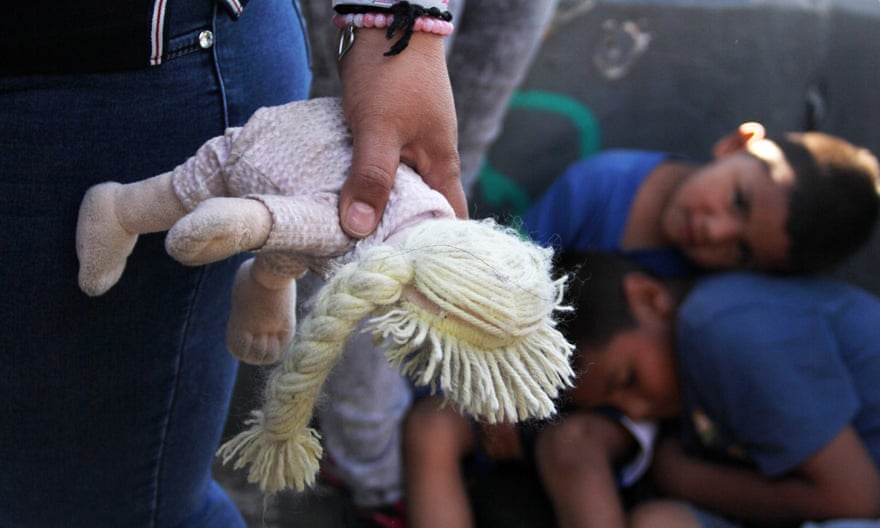 A Mexican woman holds a doll next to children at the Paso Del Norte port of entry at the US-Mexico border on 20 June 2018.