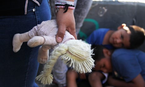 Mexican woman holds a doll next to children at the Paso Del Norte Port of Entry, in the US-Mexico border in Chihuahua state, mexico