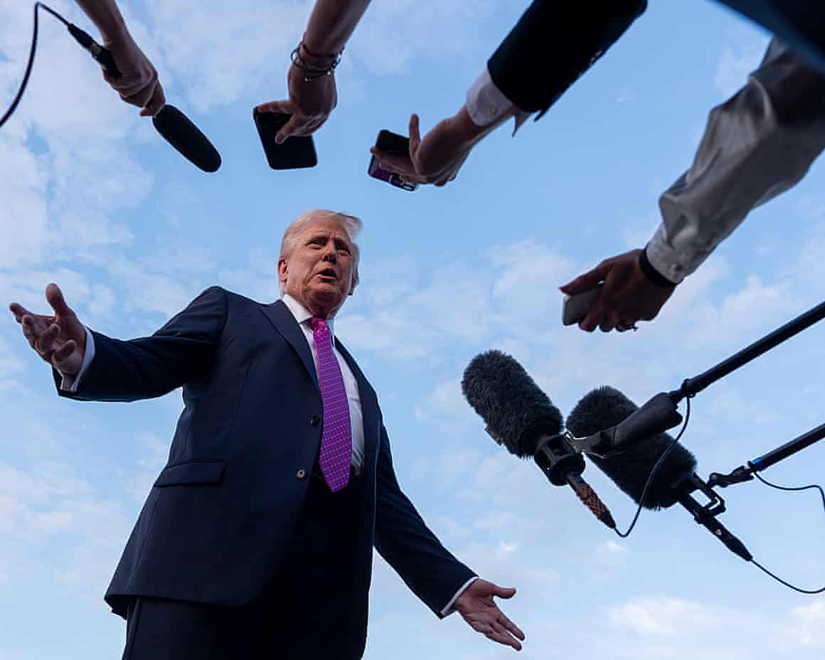 Donald Trump is surrounded by press microphones