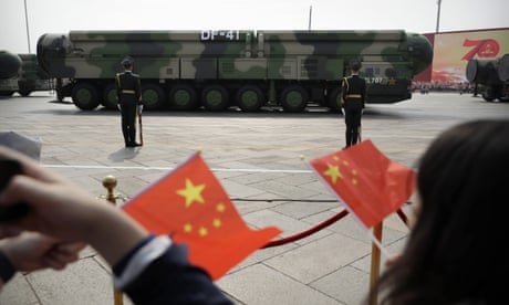 Veicoli militari cinesi che trasportano missili balistici DF-41 passano davanti a spettatori sbandieratori durante una parata a Pechino.
