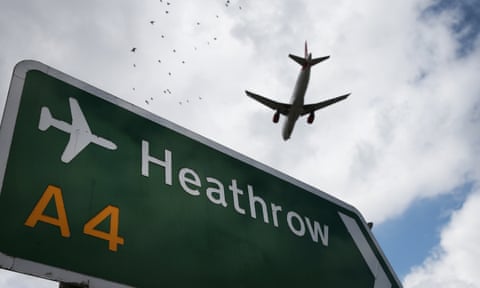 Airliner flying over a Heathrow airport sign