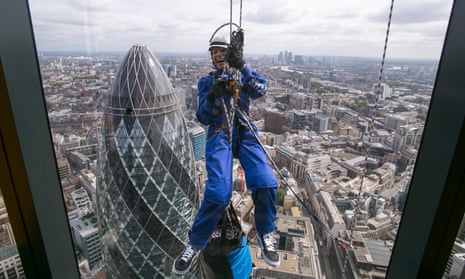 Murria wears blue jumpsuit and safety helmet. The Gherkin (30 St Mary Axe) is directly behind her, and streets of London far below that