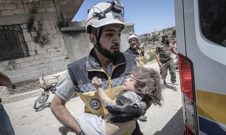 A rescue worker with a child saved from rubble in the Arihah district of Idlib after airstrikes by Russia and the Assad regime on 24 July. 