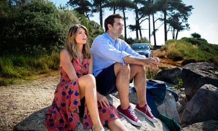 Sharon Horgan and Rob Delaney sitting on a rock, side by side, both staring straight ahead, in a scene from Catastrophe