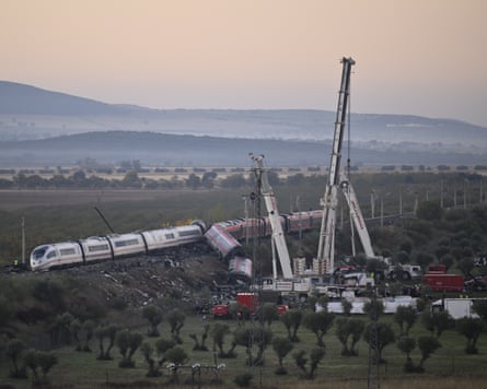 Derailed train carriages lie toppled beside cranes at the Urda, Spain, crash site.