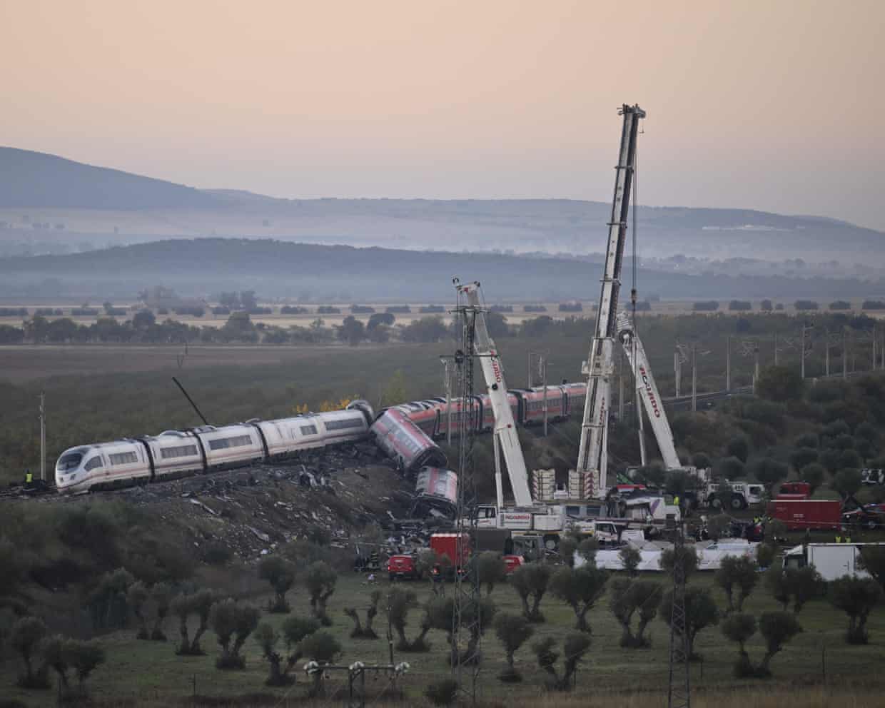 Derailed train carriages lie toppled beside cranes at the Urda, Spain, crash site.