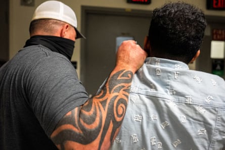 a masked grabs another man by his shirt