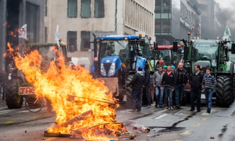 Farmers stand next to their tractors after lighting a fire during the demonstration
