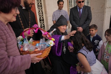 Sepuh Sargsyan blesses some children, with an Easter basket in the foreground