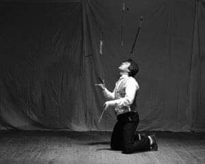 A knife thrower on his knees juggling several knives