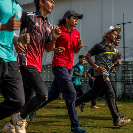 A group of players run back and forth across a pitch at the Vasoo Paranjape Cricket Academy during the physical part of their training session.