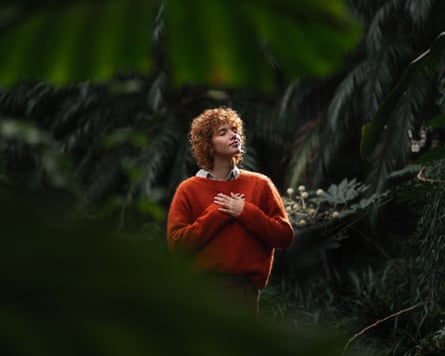 Woman standing in forest with hands on chest and eyes closed, breathing with calm and peace