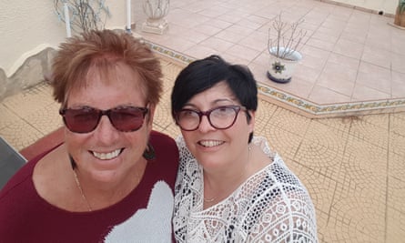 Two women look up at a camera above them, smiling for a photograph