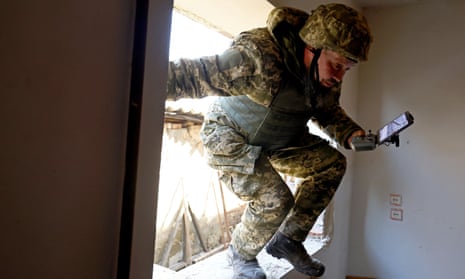 A Ukrainian serviceman jumps through a window as he carries a drone controller near the frontline of Vuhledar.